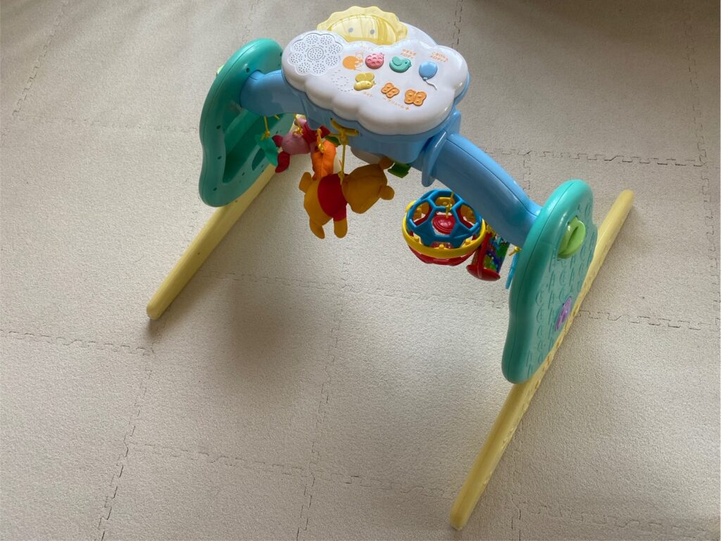 リビングのマットに置いたプーさんメリー。0〜1歳のあそびに活躍した定番おもちゃ。