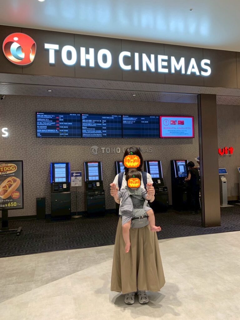 TOHOシネマズのロビー前で、ヒップシートとリュックで入場準備をする親子。赤ちゃん連れ限定上映に来た記録。