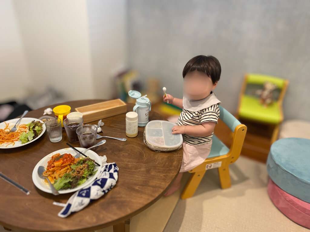子連れ専用ルームの低めテーブルで昼食をとる子どもとキッズチェア