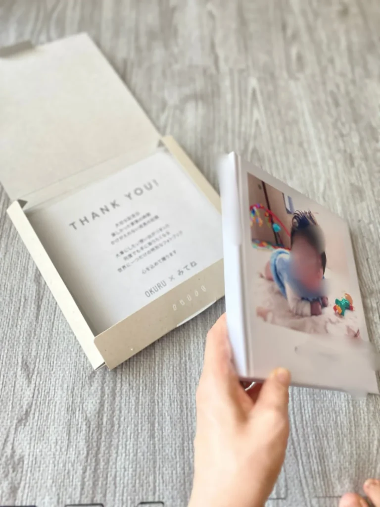 フォトブックを開封し、パッケージと表紙を手に持っている様子