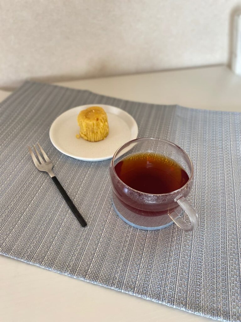 ガラスのカップの紅茶と一口サイズの焼き菓子を、ランチョンマットの上で楽しむおやつ時間。