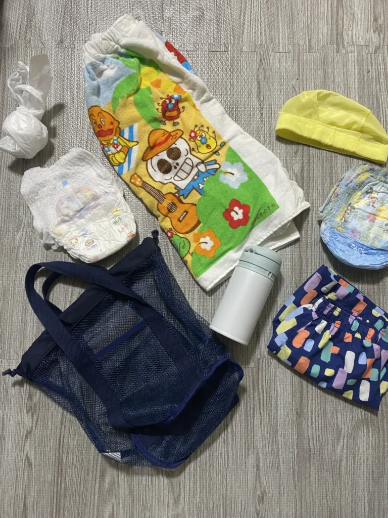 1歳児のベビースイミング持ち物一式。水着、水遊び用おむつ、スイムキャップ、巻きタオル、着替え用おむつ、水筒、濡れたものを入れる袋